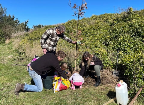 President of Alderney and young child helps Alderney Wildlife Trust CEO and Team Wilder Community Support Officer plant an oak tree within Alderney's Peace Garden